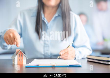 Femme d'affaires choisissant mini modèle de maison de modèle sur table en bois, planification pour acheter la propriété. Concept de choisir le meilleur. Banque D'Images
