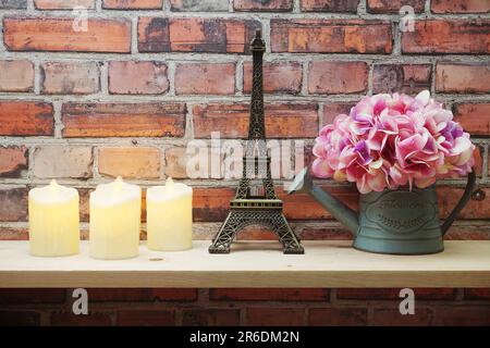 Décoration maison Tour Eiffel, bougie LED et fleur artificielle dans un pot de fleurs sur fond de baie en bois Banque D'Images