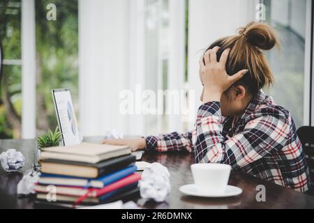 femme assise, son visage instable. Au bureau de l'ordinateur, elle a des maux de tête et du stress. Cause du travail dur et du repos insuffisant. Banque D'Images