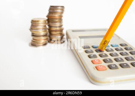 calculatrice électronique, crayon orange et piles de pièces, calcul des taxes, gros plan flou Banque D'Images