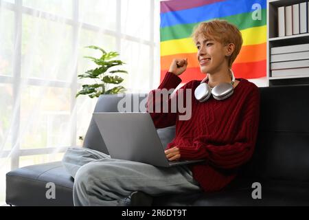 Joyeux jeune gay homme lisant de grandes nouvelles sur ordinateur portable, célébrant le succès, de nouvelles opportunités, de bons résultats d'examen Banque D'Images