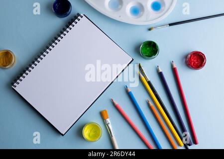 Gros plan de peintures, crayons, carnets et pinceaux avec espace de copie sur fond bleu. Retour à l'école, art, peinture, matériel scolaire, apprentissage, schoo Banque D'Images