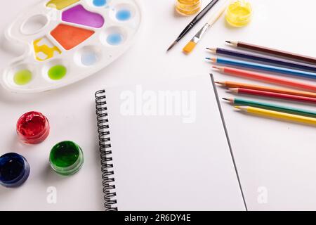 Gros plan de peintures, carnets et pinceaux avec espace de copie sur fond blanc. Retour à l'école, art, peinture, matériel scolaire, apprentissage, école et ed Banque D'Images