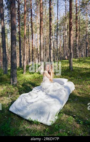 Une femme dort sur un matelas dans la forêt d'été. La fille se repose dans la nature Banque D'Images