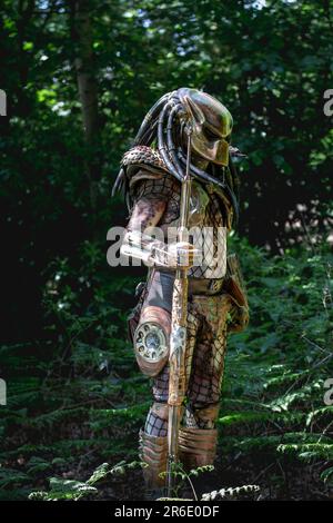 HARROGATE, ROYAUME-UNI - 3 JUIN 2023. Portrait d'un cosplayer habillé comme un étranger Predator en costume réaliste en plein air dans un environnement boisé Banque D'Images