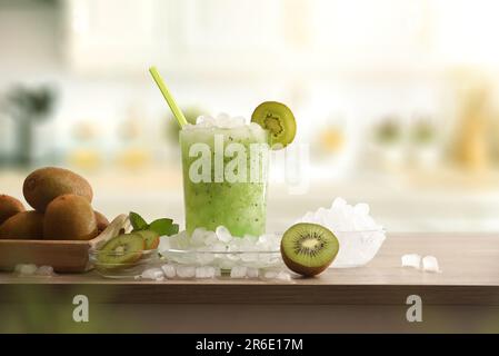 Détail de la boisson froide au kiwi avec beaucoup de glace sur un banc de cuisine en bois avec des fruits coupés et un bol avec de la glace autour d'elle. Vue avant. Composition horizontale Banque D'Images