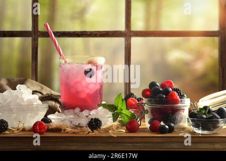 Boire avec des baies avec des fruits et de la glace autour d'elle sur une table en bois et un fond de fenêtre. Vue avant. Composition horizontale. Banque D'Images