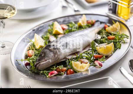 Poisson cru au bar de mer placé sur un plateau argenté sur une salade verte, rouge et jaune. Banque D'Images