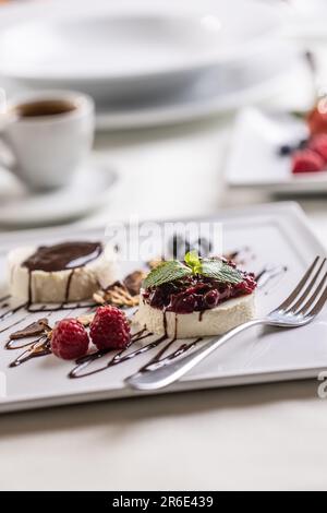 Panna cotta aux baies de la forêt et au chocolat servi dans un café avec un café. Banque D'Images