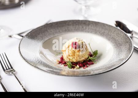 Crème au chocolat blanc aux amandes et à la noix de coco servie avec des framboises. Banque D'Images