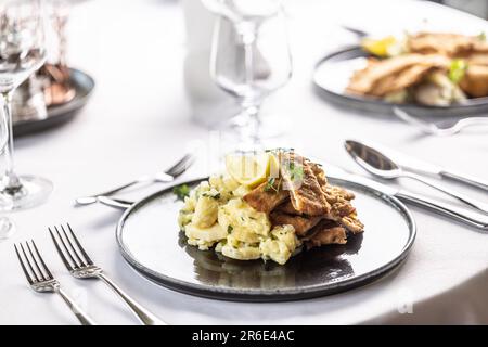 Le schnitzel de Wiener est coupé en morceaux et servi sur un tas de salade de pommes de terre. Banque D'Images