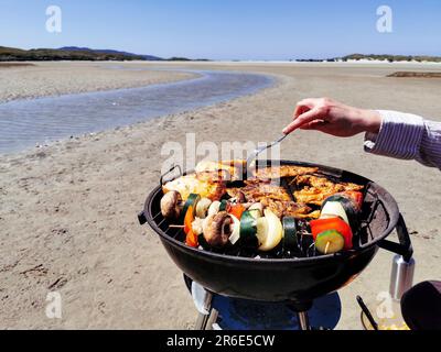 Faire un barbecue sur une plage de sable entourée de montagnes à Silver Strand, Thallabawn, Doovilra, Louisburgh, Co Mayo, Irlande Banque D'Images