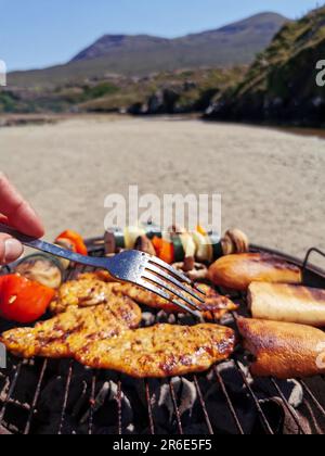 Faire un barbecue sur une plage de sable entourée de montagnes à Silver Strand, Thallabawn, Doovilra, Louisburgh, Co Mayo, Irlande Banque D'Images