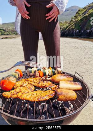 Faire un barbecue sur une plage de sable entourée de montagnes à Silver Strand, Thallabawn, Doovilra, Louisburgh, Co Mayo, Irlande Banque D'Images