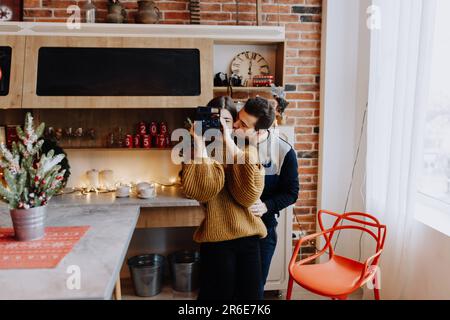 jeune couple est photographié serrant dans la cuisine pendant noël Banque D'Images