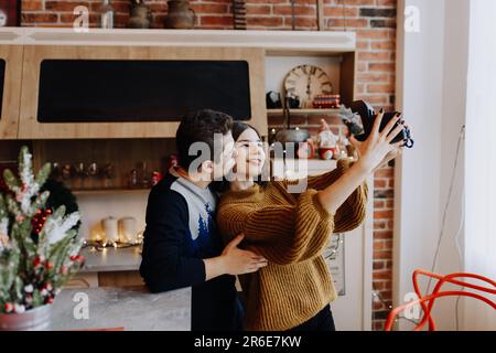 jeune couple est photographié serrant dans la cuisine pendant noël Banque D'Images