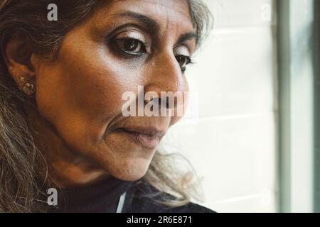 Gros plan d'une femme indienne mûre et attirante qui a l'air pensive Banque D'Images