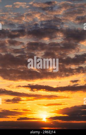 Le ciel est mis à feu avec des couleurs éclatantes dans cette photo étonnante. Les nuages reflètent la lueur chaude du soleil couchant, créant un éclat et un captivant Banque D'Images