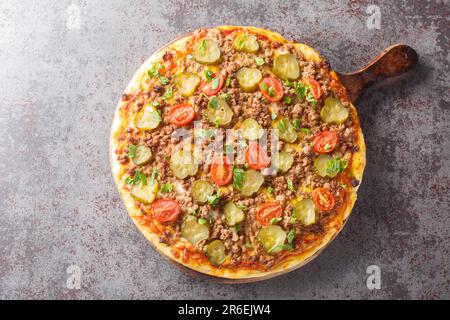 Tasty Pizza est recouvert d'une sauce crémeuse à hamburger, de bœuf haché, de fromage et de cornichons sur le panneau en bois de la table. Vue horizontale du dessus à partir d'un Banque D'Images