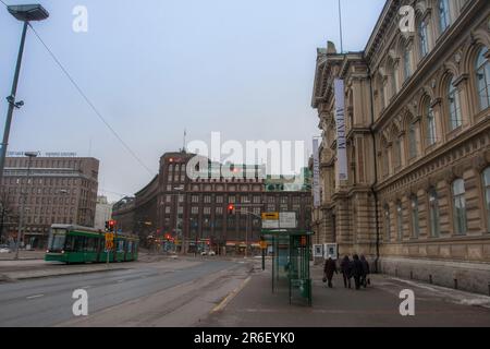 Vue sur la rue du centre-ville d'Helsinki en hiver tôt le matin. Le tramway HSL passe à côté tandis que les piétons marchent le long du sentier. Helsinki, Finlande Banque D'Images