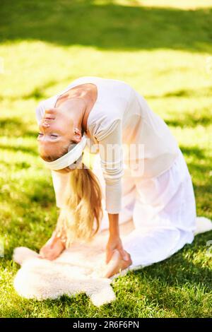Belle femme en bonne santé pratiquant le yoga dans le parc d'été ou le jardin, l'ustrasana ou la pose de chameau Banque D'Images
