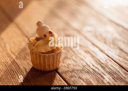 Cupcake délicieux mignon pour bébé avec crème au fromage, garniture au sucre et pattes de lapin sur table en bois. Gâteau doux et amusant avec banny. Cuisine et fête d'enfants conc Banque D'Images