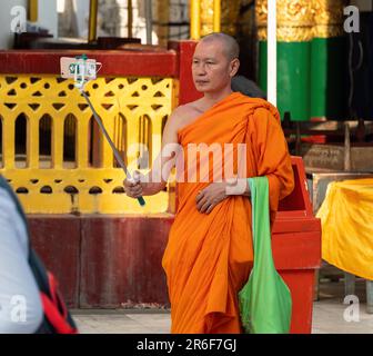 Moine bouddhiste prenant un selfie à la Pagode Shwedagon, le monument le plus célèbre de Yangon, au Myanmar. Banque D'Images