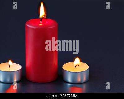 trois bougies allumées assises l'une à côté de l'autre sur une table. . Banque D'Images
