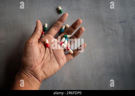 Gros plan de la main et des pilules sur un sol en béton avec espace de copie. Surdose, addict de drogue et concept de suicide Banque D'Images