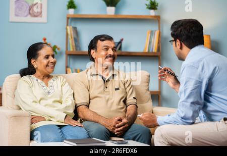Banquier indien professionnel expliquant au sujet de la police d'assurance à un couple senior à la maison - concept de conseiller financier, d'expert d'affaires et de banque Banque D'Images