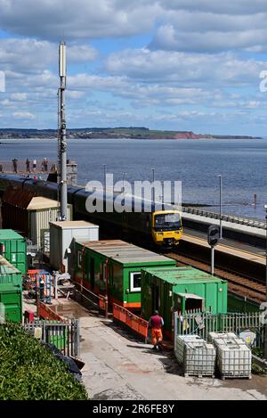 Un train passant par la gare de Dawlish pendant la construction travaille à la construction d'une nouvelle plate-forme et d'une passerelle en 2023. Banque D'Images