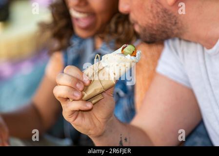 l'homme tient un burrito vegan dans sa main à côté d'une femme ayant le bon temps-aucun visage Banque D'Images