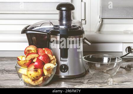 Une pléthore de pommes mûres sur un comptoir de cuisine à côté d'une centrifugeuse Banque D'Images