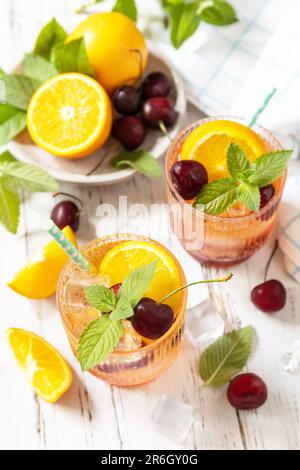 Boisson rafraîchissante glacée à la limonade au cola à la cerise orange ou cocktail mojito sur une table en bois. Boisson fraîche d'été. Banque D'Images