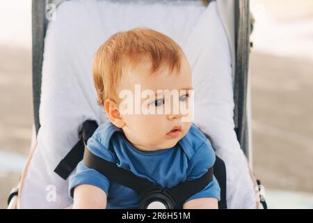 Portrait en gros plan à l'extérieur d'un adorable bébé à tête rouge assis dans un buggy Banque D'Images