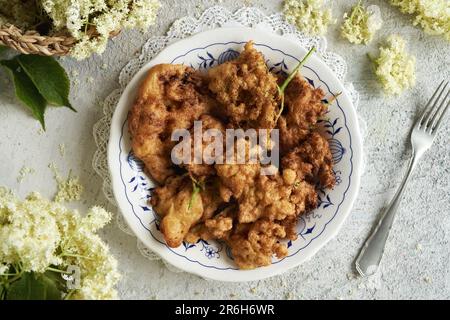 Une assiette de fleurs de baies de sureau frite en pâte, vue du dessus Banque D'Images