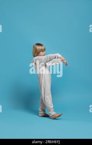 Un garçon en pyjama marche sur fond bleu clair Banque D'Images