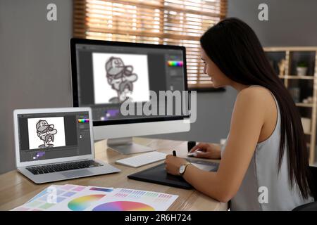 Animator travaillant avec une tablette graphique, un ordinateur et un ordinateur portable. Illustrations à l'écran Banque D'Images