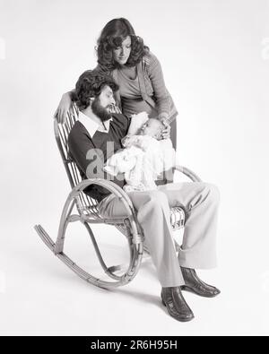 1970S PÈRE DE FAMILLE ASSIS DANS UN ROCKER BENTWOOD TENANT LA BÉBÉ MÈRE DEBOUT À CÔTÉ D'EUX TOUCHANT LA TÊTE DU BÉBÉ - B25518 HAR001 HARS 1 COMMUNICATION JUVÉNILE JEUNE ADULTE TRAVAIL D'ÉQUIPE ENFANTS FAMILLES JOIE STYLE DE VIE FEMMES MARIÉ STUDIO SHOT ROCKER CONJOINT ÉPOUX SAINTETÉ MAISON LIFE LUXURY COPY SPACE AMITIÉ DEMI-LONGUEUR FEMMES PERSONNES S'OCCUPANT HOMMES PÈRES B&W PARTENAIRE MOUSTACHE BONHEUR BAMBOU MOUSTACHES BALANÇANTE CHAISE DADS FIERTÉ VISAGE CHEVEUX AFFECTUEUX CONNEXION TENDRE COURBÉ À CÔTÉ DE BÉBÉ ÉLÉGANT GARÇON BENTWOOD TENDRESSE BARBE COOPÉRATION CROISSANCE JEUNES MÈRES TOGETHNESS ÉPOUSES Banque D'Images