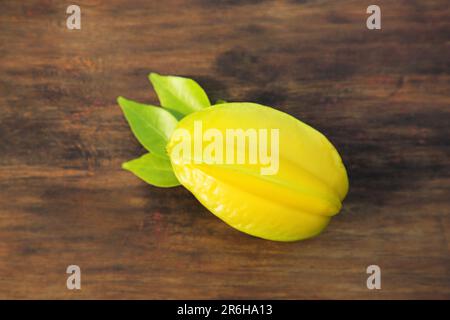 Une délicieuse carambola mûre avec des feuilles sur une table en bois, vue sur le dessus Banque D'Images