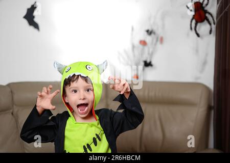 Un petit garçon heureux en costume de monstre a osé ses dents et veut faire peur. Carte postale Halloween. Banque D'Images