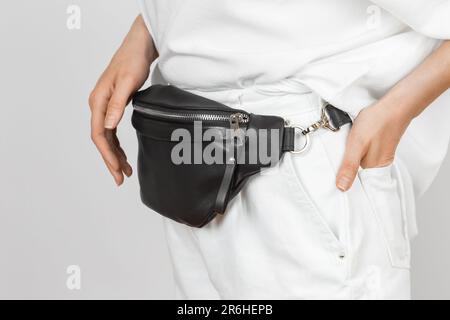 Sac de taille en cuir noir sur une femme portant un Jean et une chemise blancs. Articles d'accessoires en cuir faits main Banque D'Images