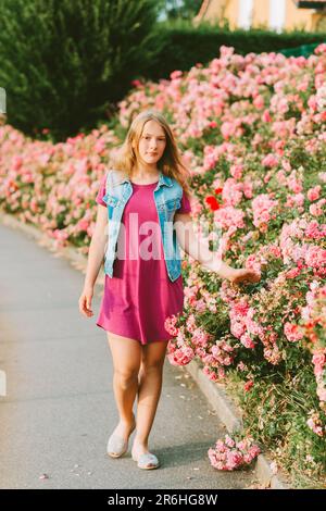 Portrait extérieur de la jeune fille mignonne, enfant préadolescent dans le jardin de roses Banque D'Images