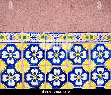 Image horizontale d'une mosaïque traditionnelle jaune, bleue et blanche peinte à la main sur un mur en stuc à Santa Fe, Nouveau-Mexique, États-Unis. Banque D'Images