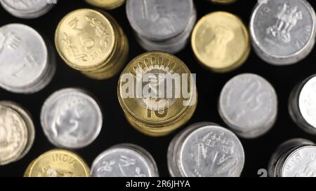 vue de dessus gros plan de pièces de monnaie de roupie indienne en or et en argent disposées de près empilées dans des rangées isolées dans un fond noir Banque D'Images