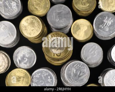 vue de dessus gros plan de pièces de monnaie de roupie indienne en or et en argent disposées de près empilées dans des rangées isolées dans un fond noir Banque D'Images