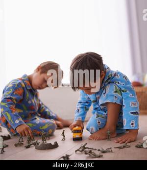 Jeunes garçons, jouant et jouets ensemble en pyjama pour s'amuser avec des figurines d'action miniature, voiture jouet ou jeux. Frères, enfants frères et famille Banque D'Images