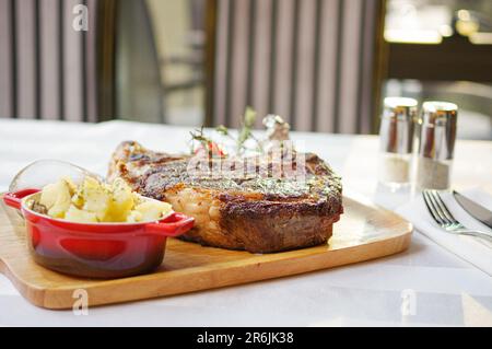 Steak grillé au romarin de tomates et purée de pommes de terre sur un plateau en bois Banque D'Images