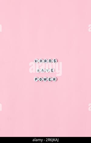 Vue de dessus des citations « Words ont power » faites de perles sur fond rose. concept de motivation et de réussite Banque D'Images