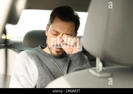 Homme endormi et fatigué assis dans une voiture moderne Banque D'Images